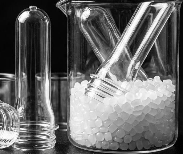 PET preforms and a beaker of resin pellets in black and white